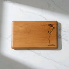 Wooden cutting board with floral design and 'Woodshire' branding on a marble surface