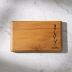 Wooden cutting board with engraved design and 'WOODFALK' branding on a marble surface