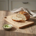 Sliced bread on a wooden cutting board with a bowl of spread on a wooden table.