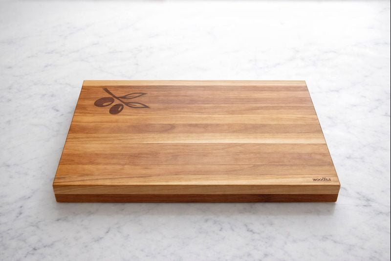 Wooden cutting board with olive design on a marble surface