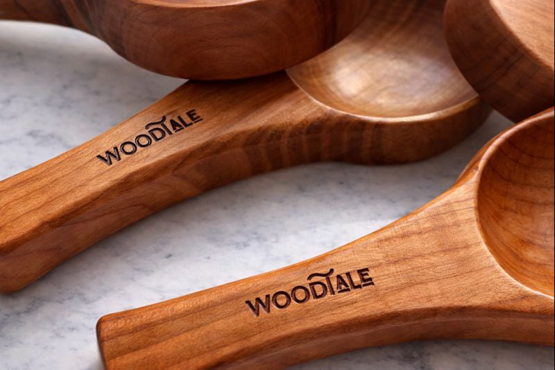 Wooden measuring spoons with 'WOODTALE' branding on a marble surface