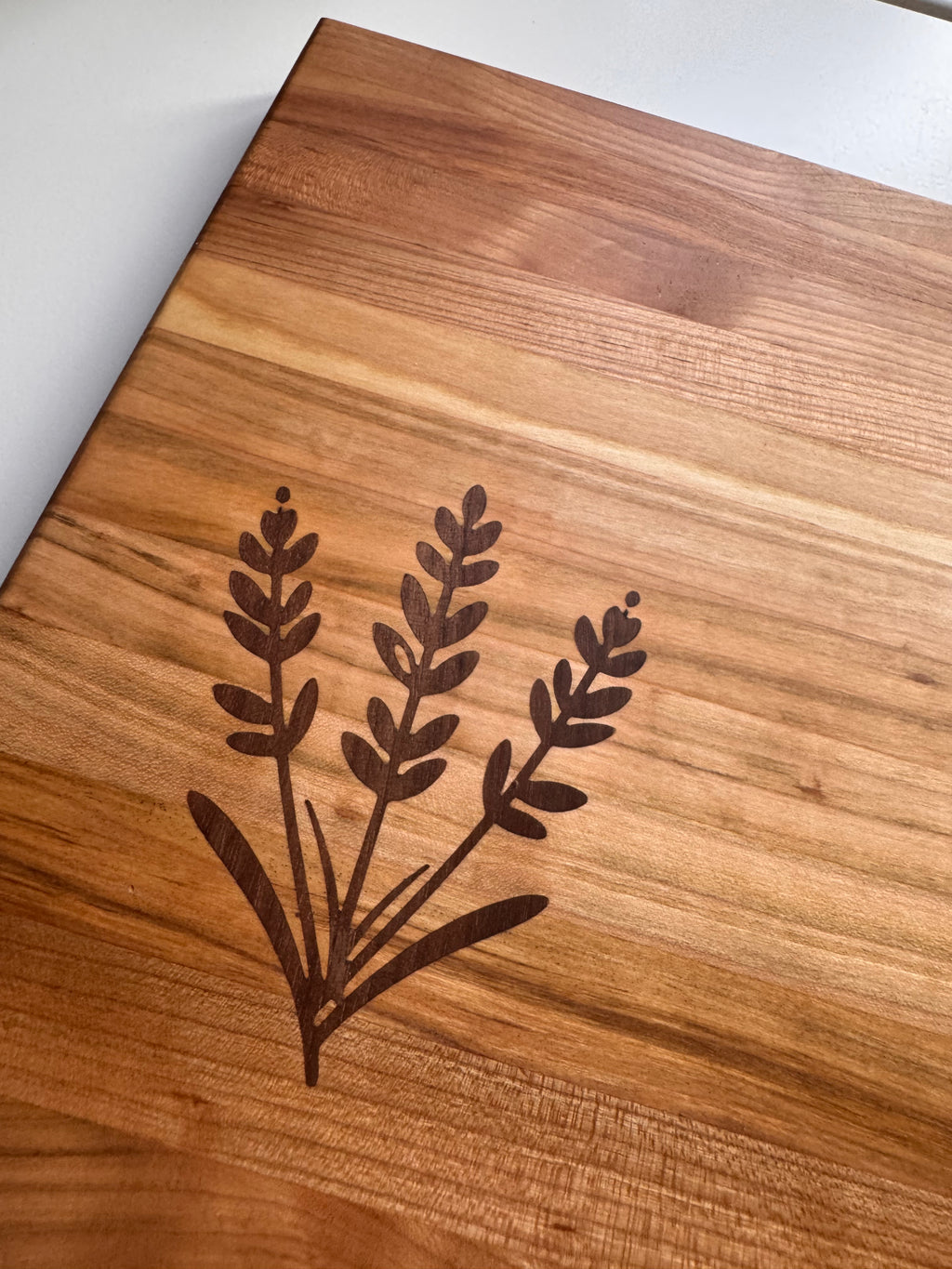 Wooden cutting board with laser-engraved plant design on a white background