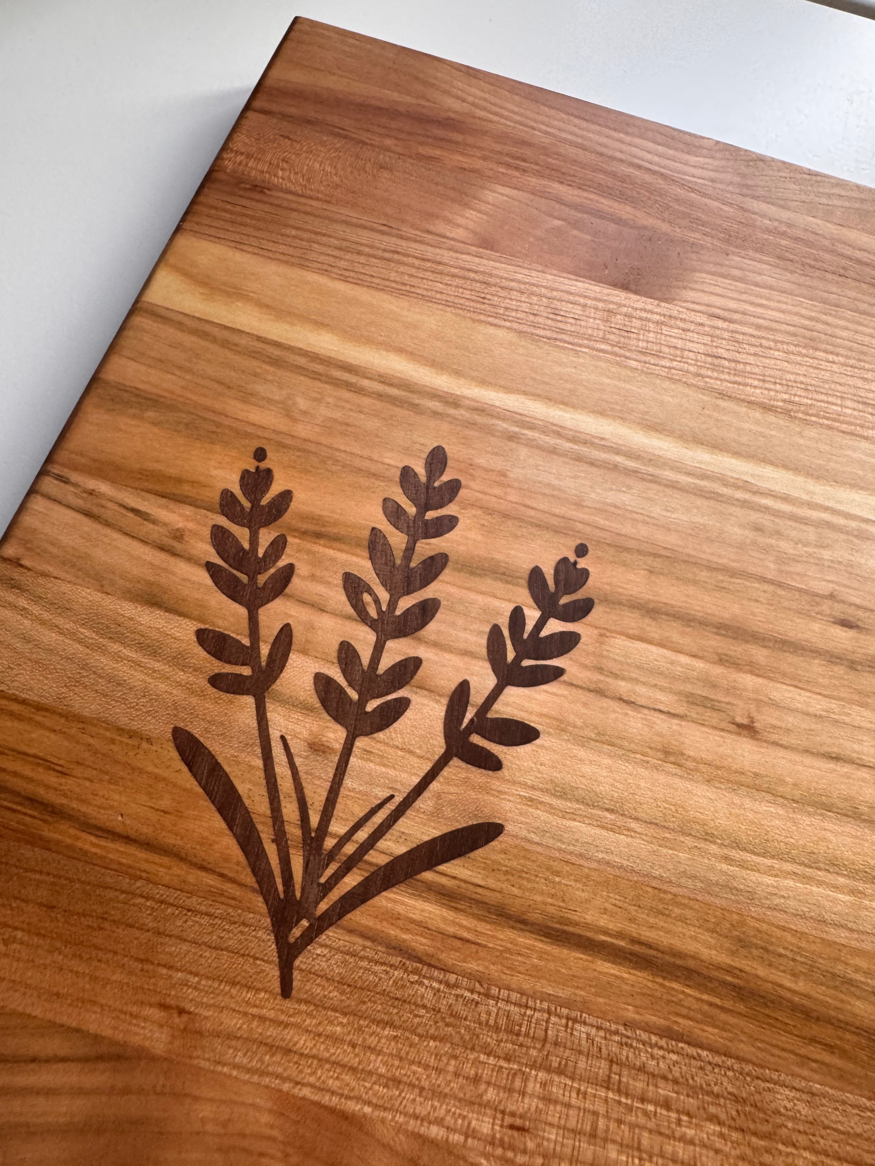 Wooden cutting board with laser-engraved plant design on a white background