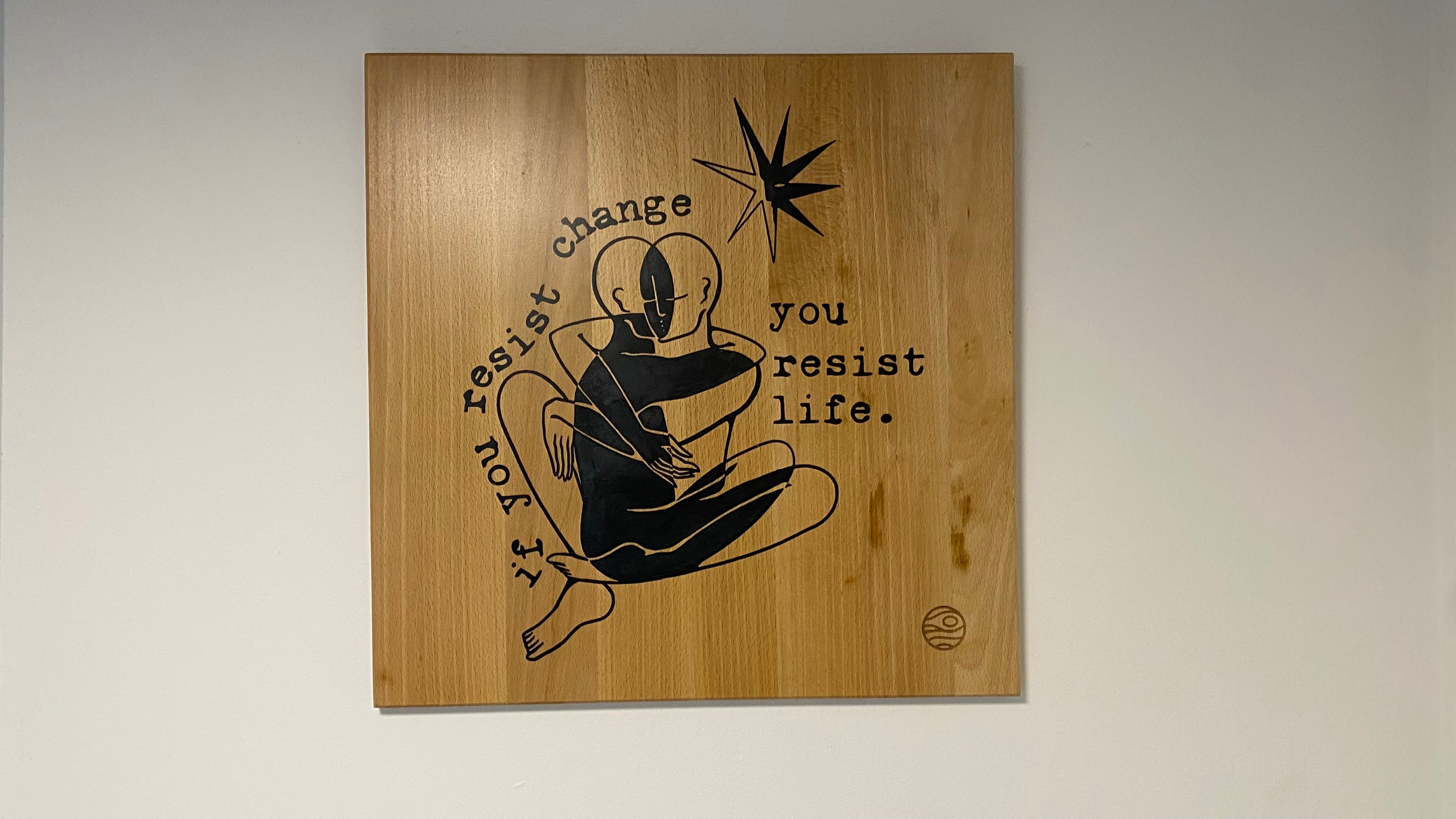 Wooden plaque with black text and graphic on a light gray background