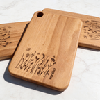 Wooden cutting boards with engraved plant designs on a light background