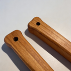 Two wooden handles with holes on a light gray background